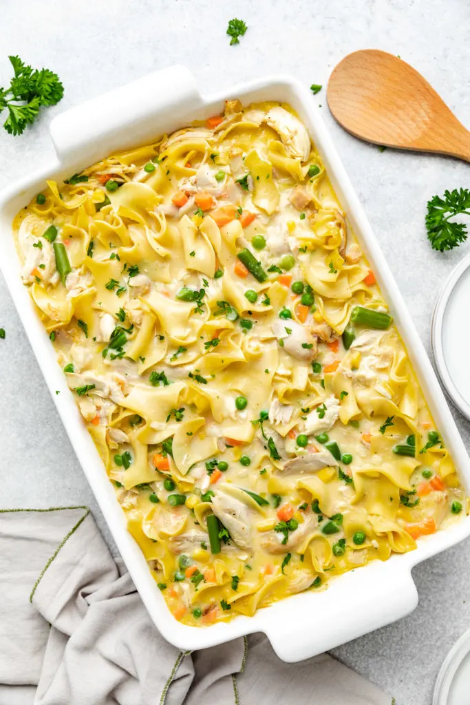 Top down view of baked chicken and noodle casserole in a white dish.