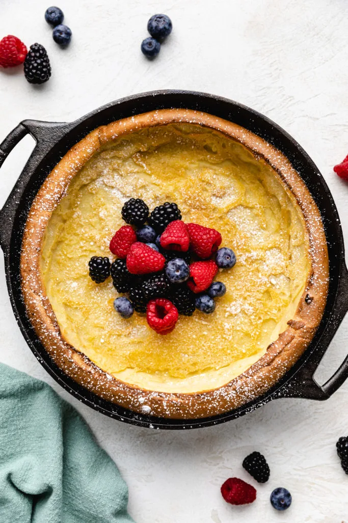 Close up view of a dutch baby pancake with fruit in a cast iron pan.