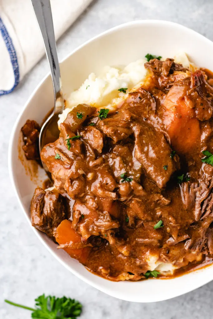 Close up view of stew with guinness over mashed potatoes.