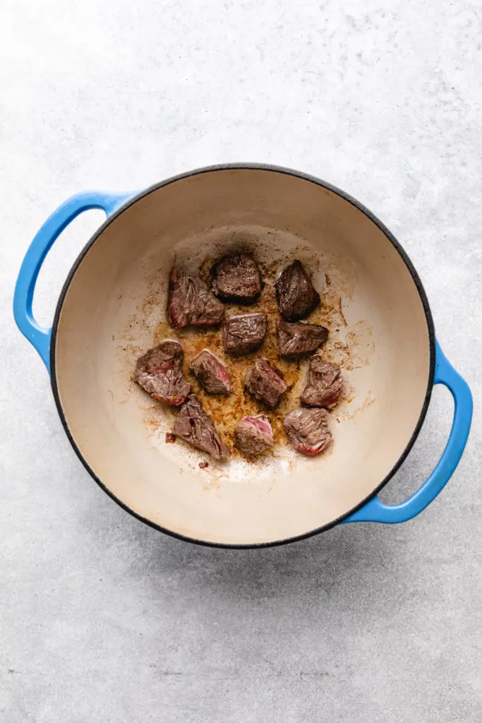 Cubed beef cooking in a pan.