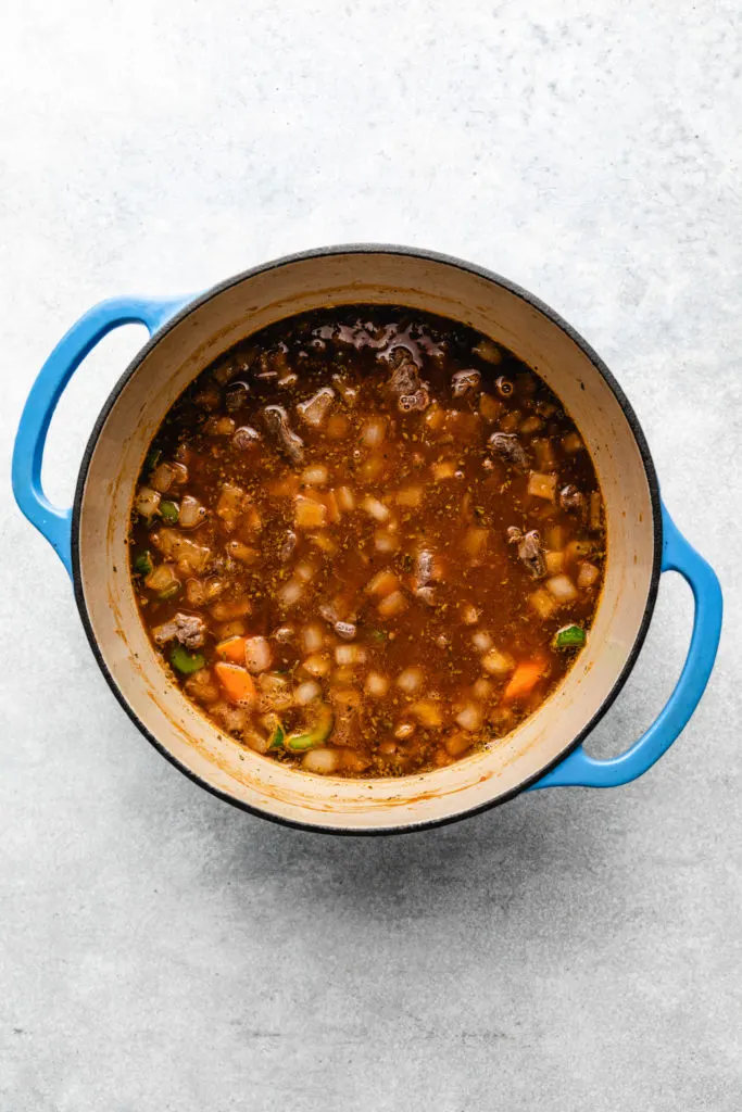 Cooked beef added to a pan of stew ingredients.