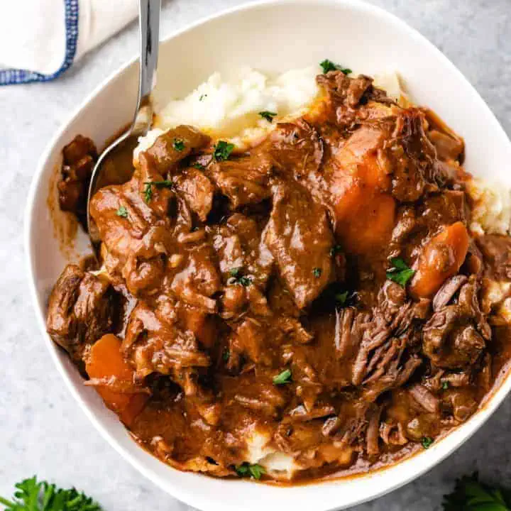 Top down view of a mashed potatoes topped with irish stew with beef.