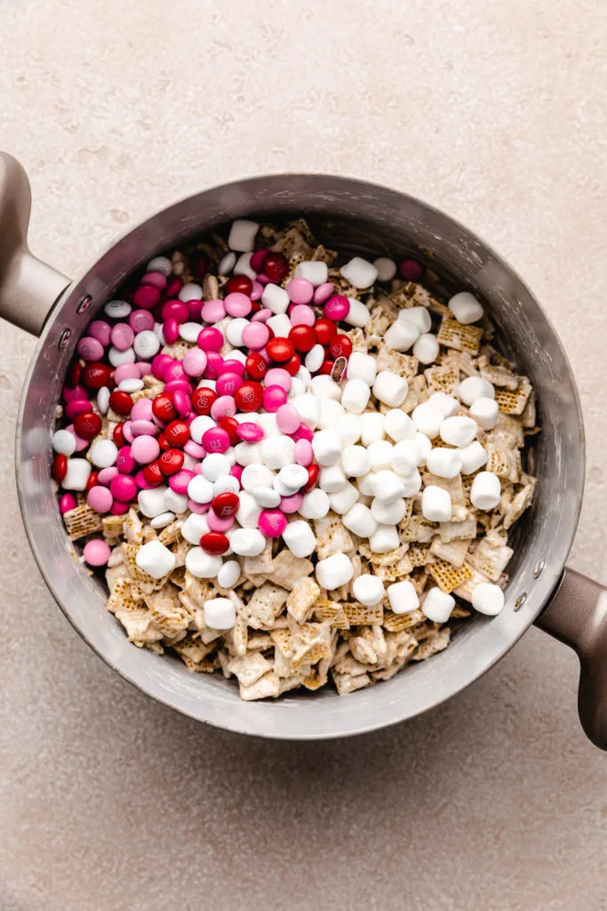 M&ms and marshmallows added to a pan of cereal bars.