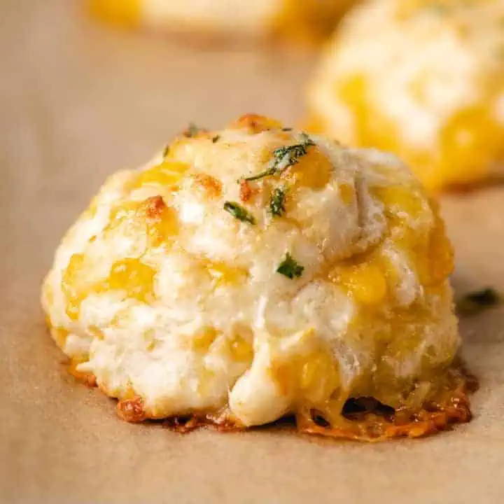 Close up view of a cheddar bay biscuit on brown parchment paper.