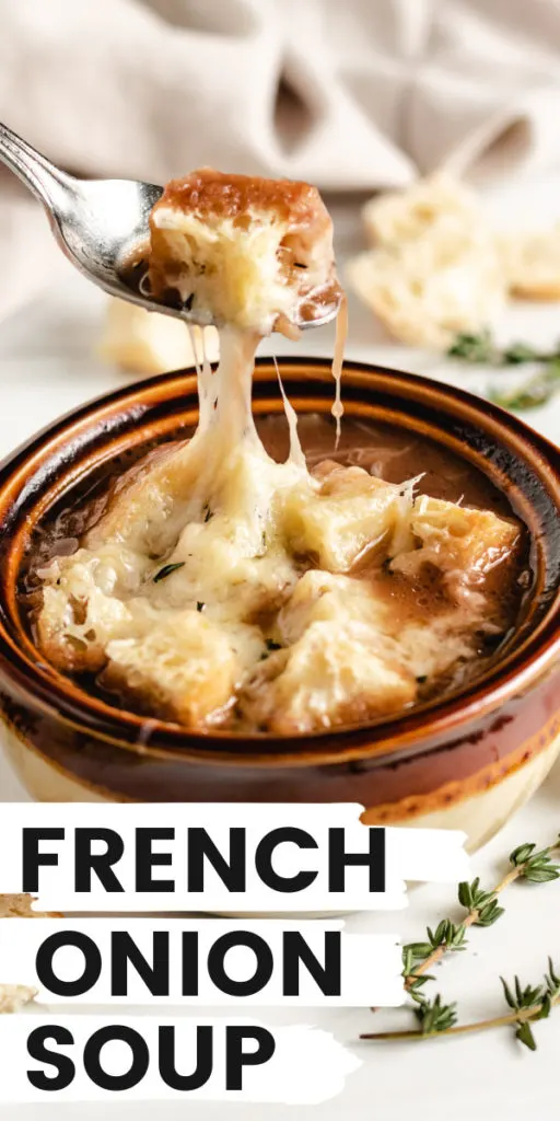 Close up view of a spoon holding up a bite of french onion soup.