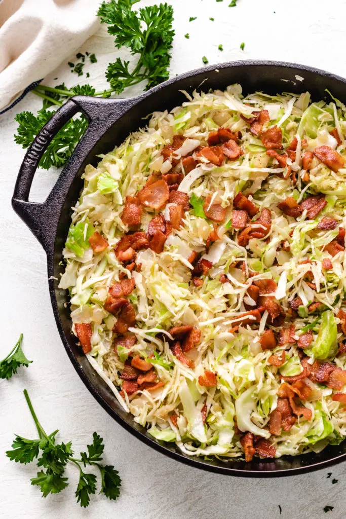 Crumbled bacon on top of a pan of shredded cabbage.