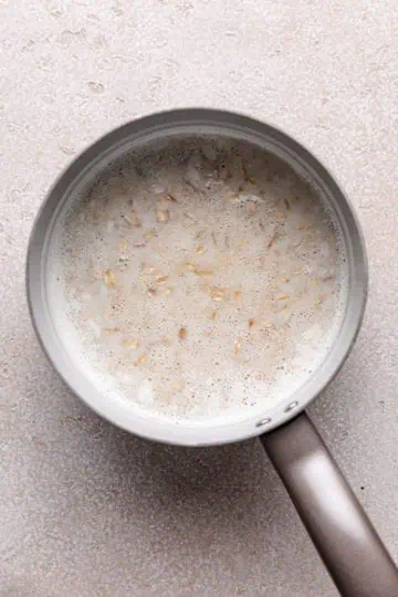 Oats poured into a pan of milk and water.