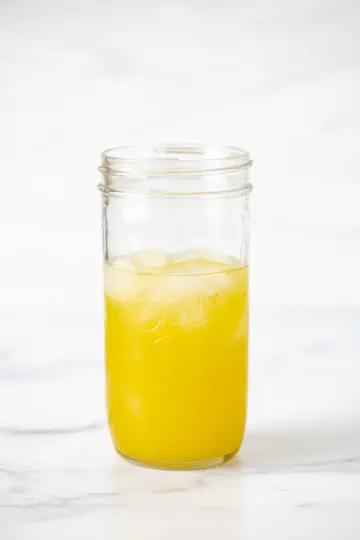 Pineapple juice, vodka, and amaretto in a jar.