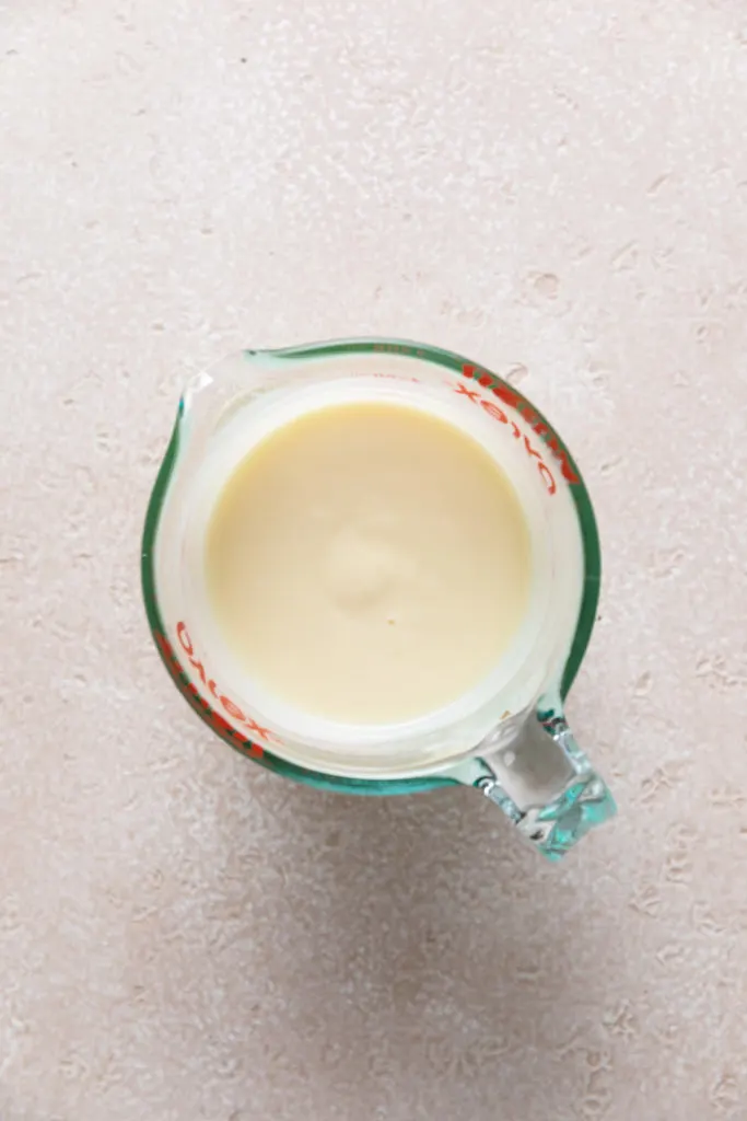 Top down view of lemon glaze in a measuring cup.