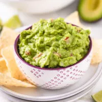 Close up view a bowl of dip next to chips.