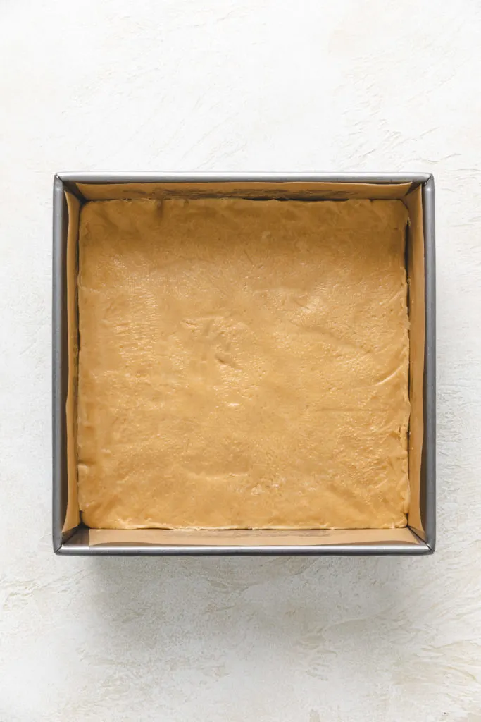 Peanut butter fudge pressed into a pan.