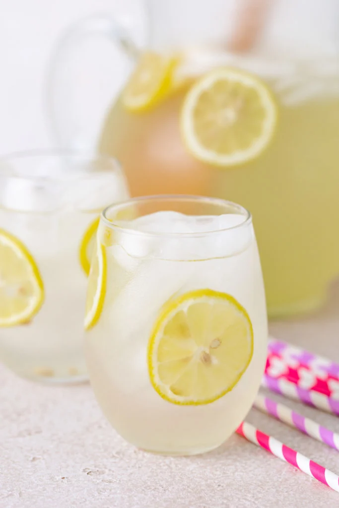 Colorful straws next to a glass of lemonade.