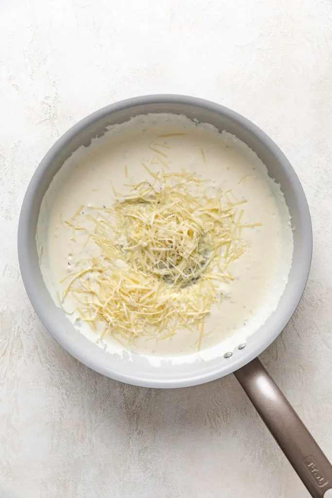 Parmesan cheese added to a creamy pasta sauce.