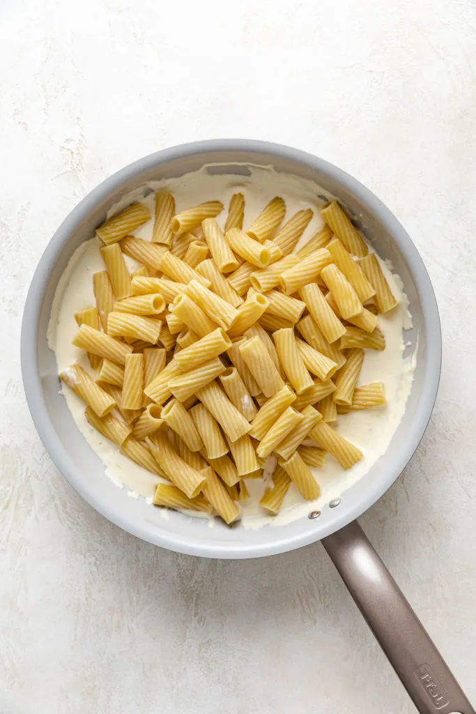 Pasta noodles poured over a creamy sauce.