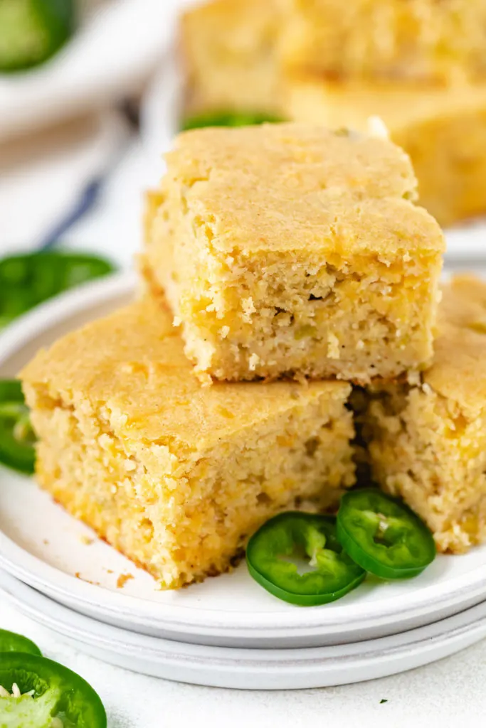 Angled view of cornbread with cheese and green chiles on a couple of plates.