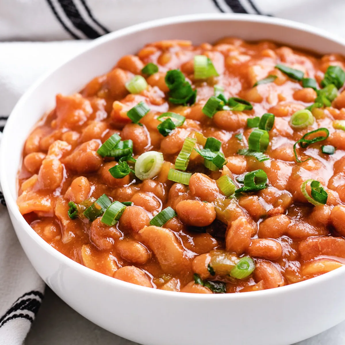 White serving dish full of crock pot baked beans.