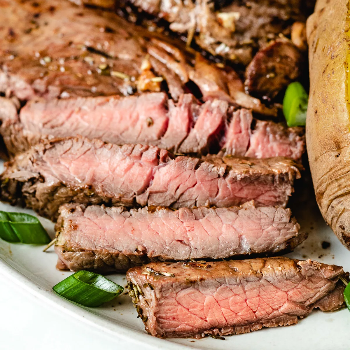 Close up view of sliced sirloin steak on a plate.