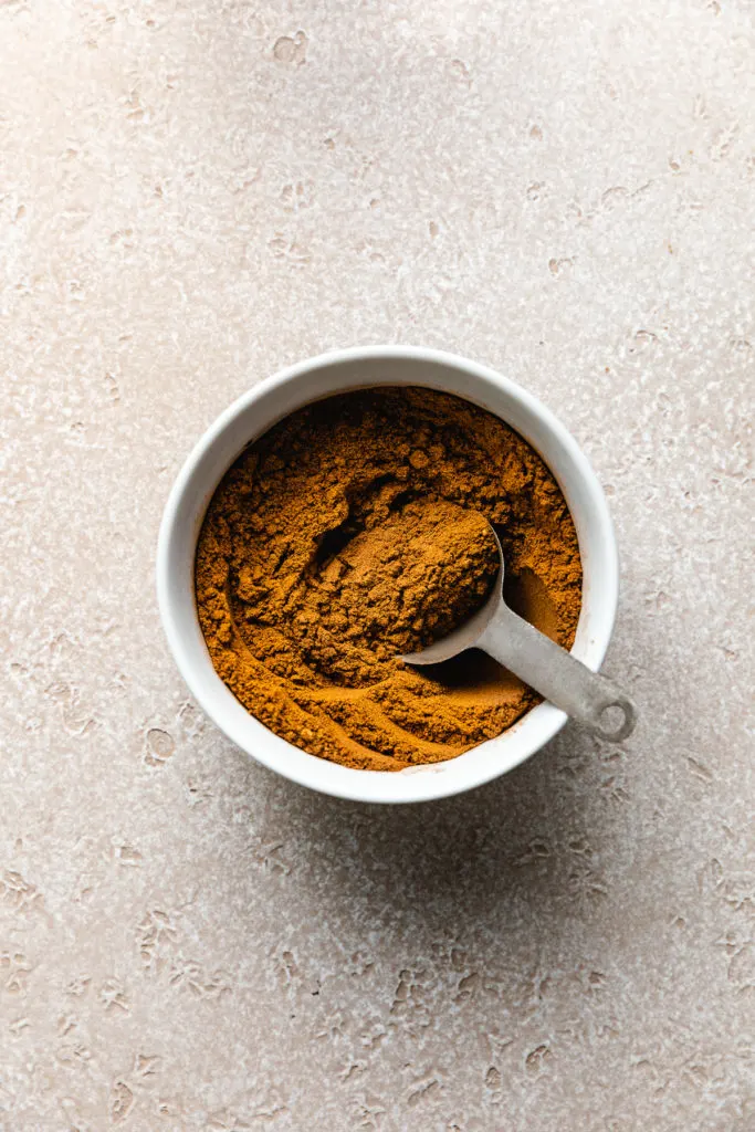 Pumpkin pie spice in a bowl with a measuring spoon.