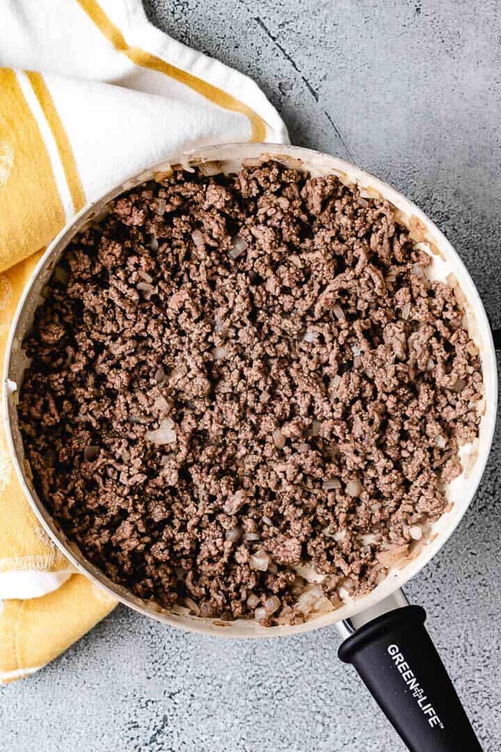 Top down view of ground beef and onions in a pan.