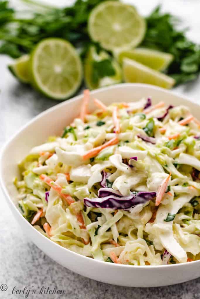 Limes next to a bowl of coleslaw.