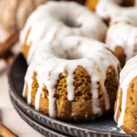 Close up view of mini pumpkin bundt cakes on a stack of plates.