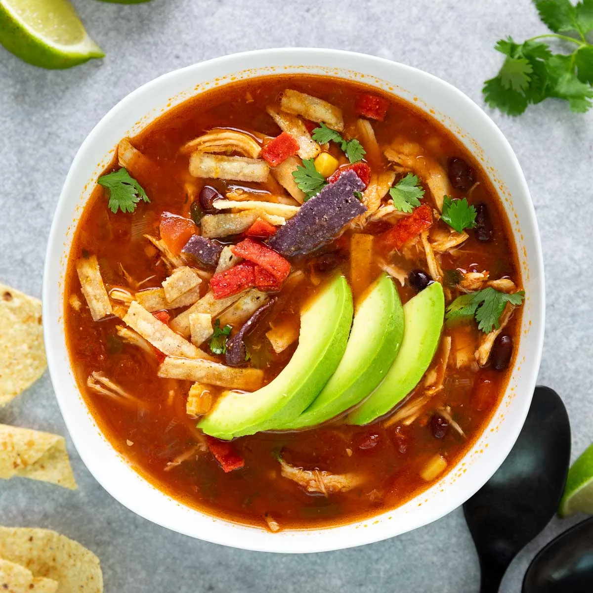 Close up view of a bowl of soup topped with sliced avocado.