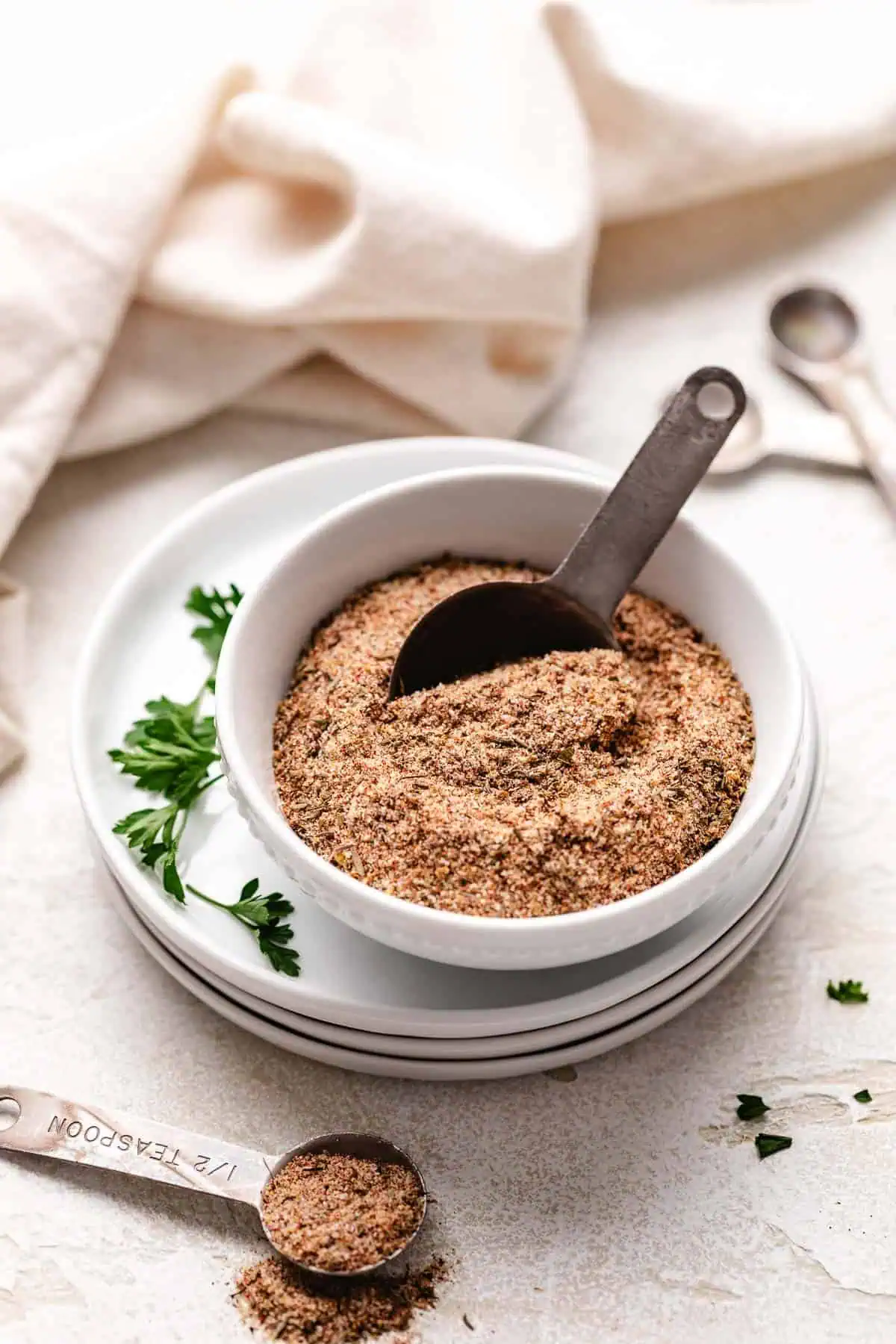 Metal measuring spoon in a bowl of seasoning blend.