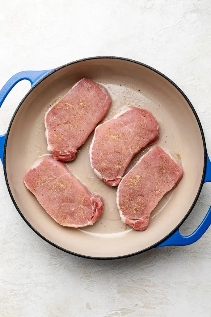 Seasoned pork chops in a pan.