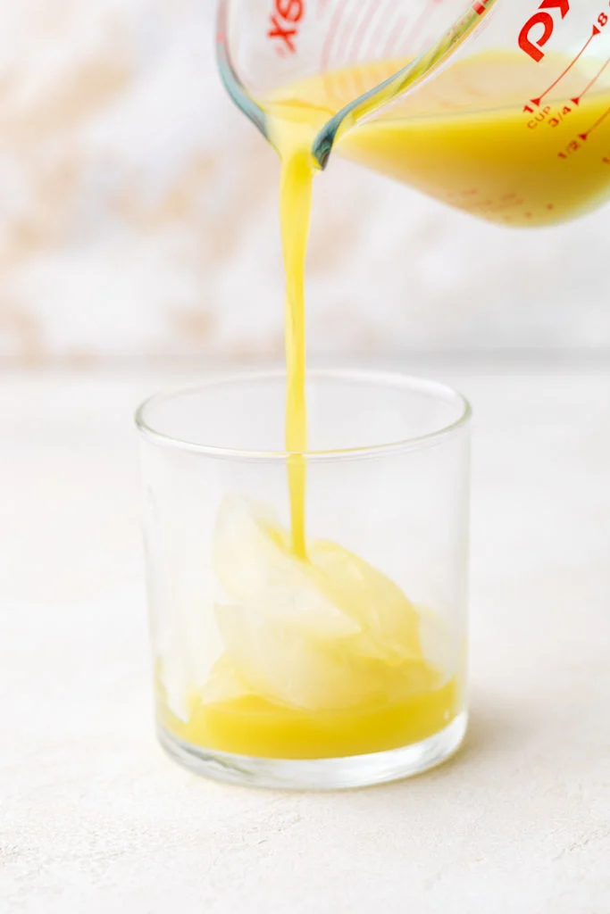 Ginger simple syrup being poured over ice.