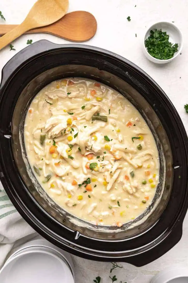 Top down view of a slow cooker filled with chicken and sauce.