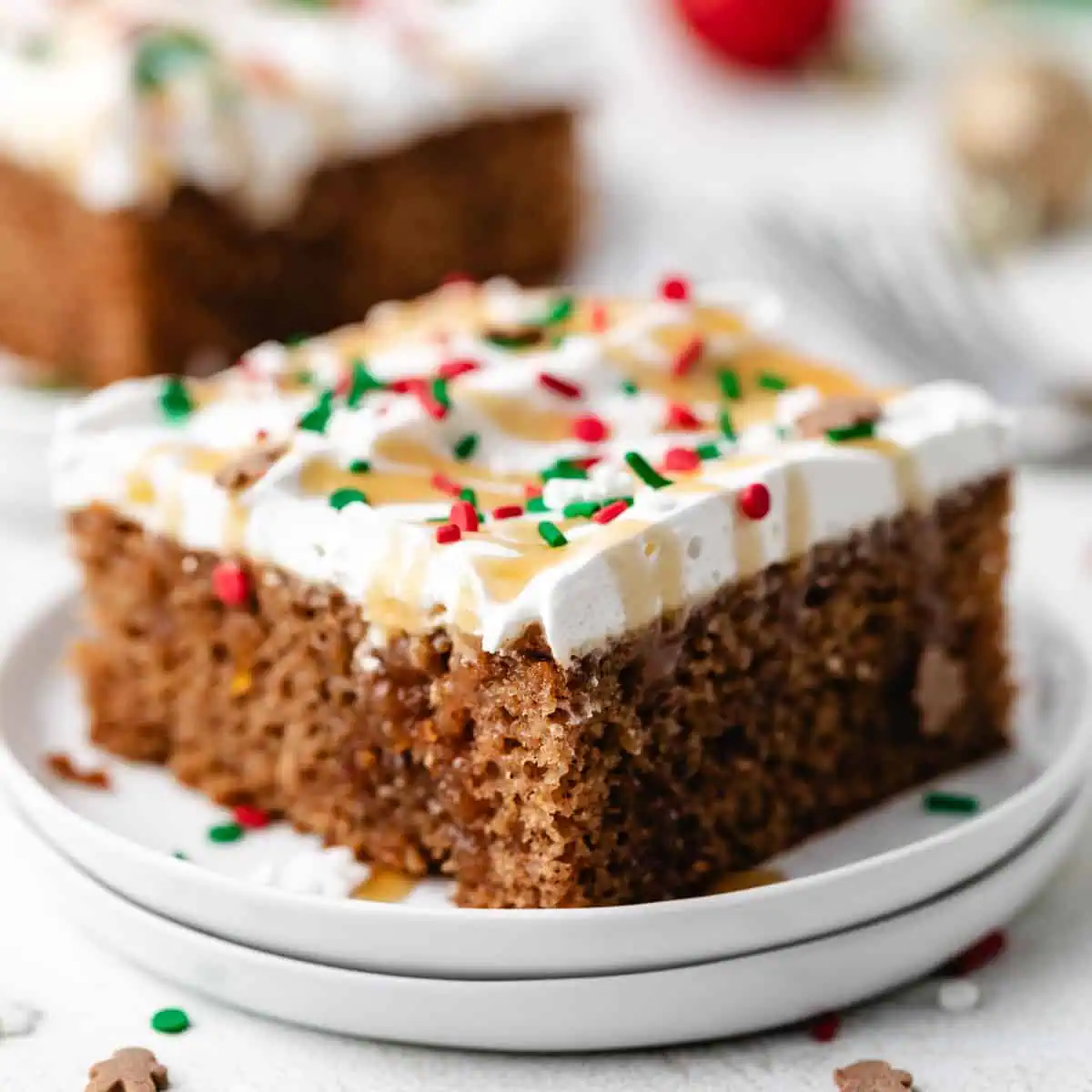 Close up view of two plates holding a piece of christmas cake with cool whip frosting.