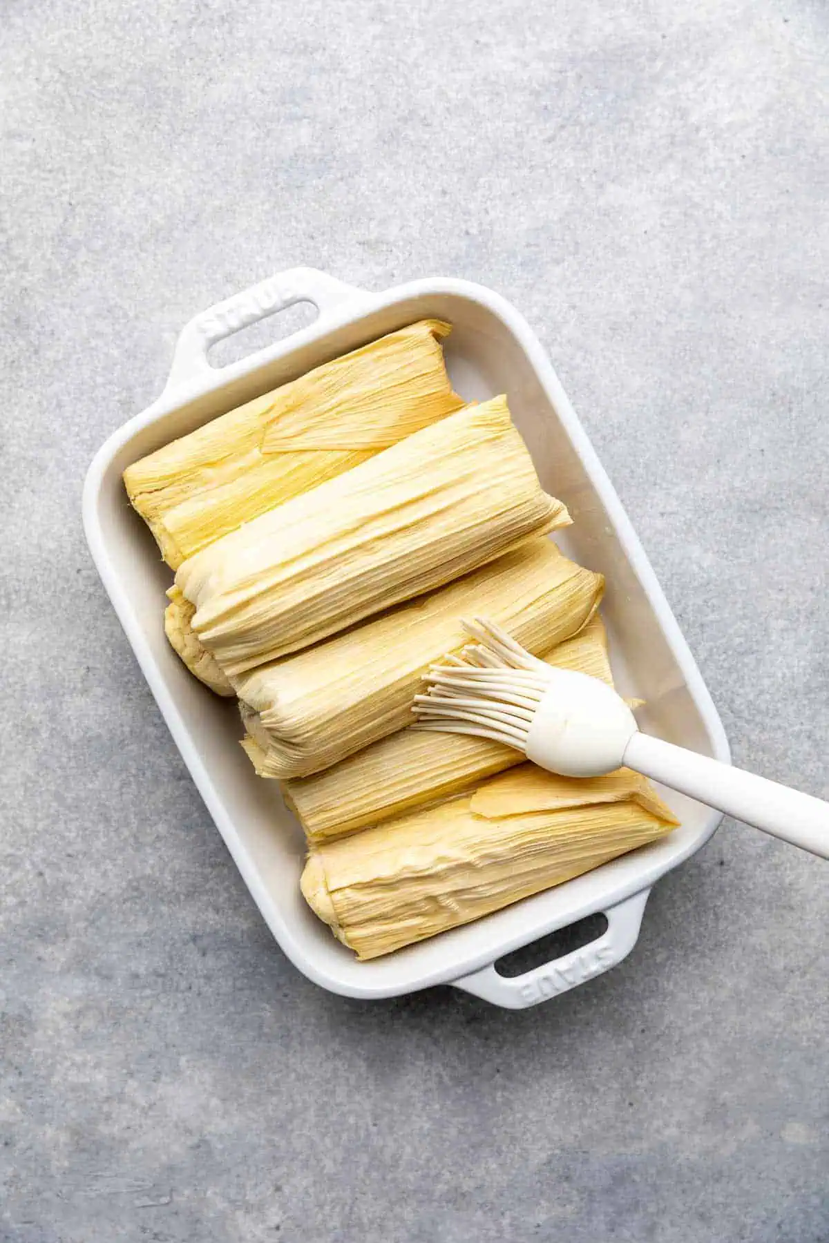 Oil being brushed onto tamales.