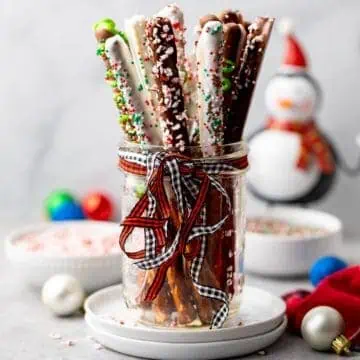 Mason jar with a ribbon filled with chocolate dipped pretzel rods.