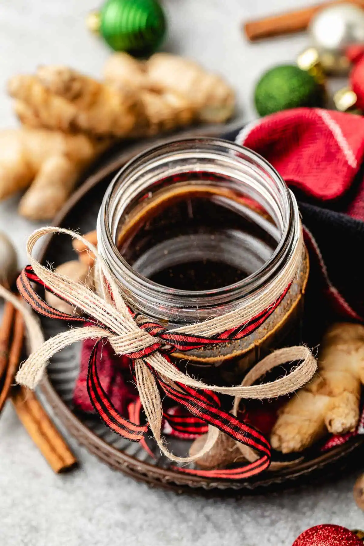 Fresh ginger root next to a jar of syrup.