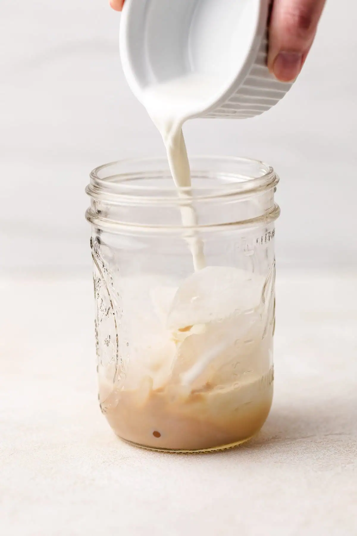 Half and half being poured into a jar with ice.