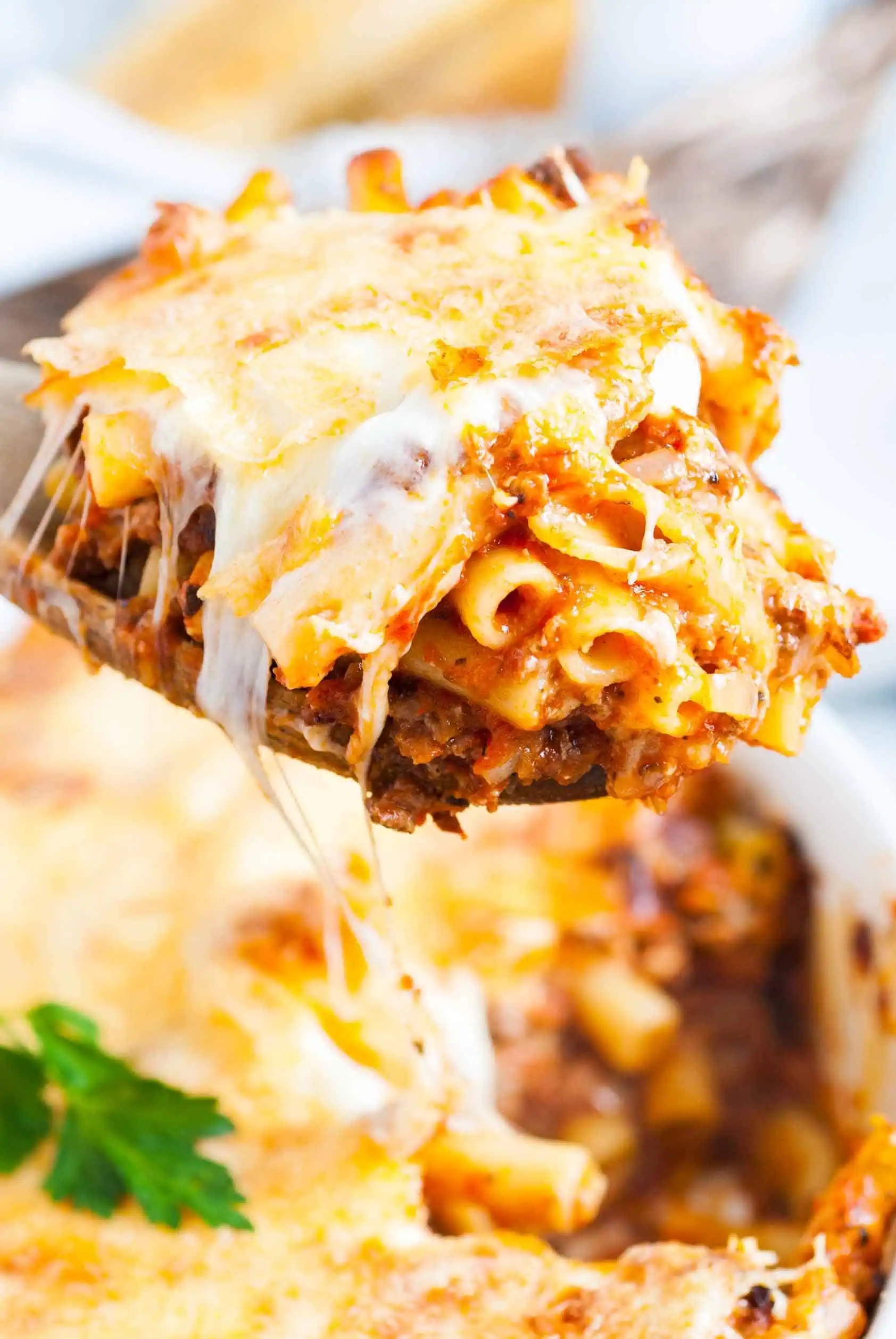 Spatula scooping baked pasta from a pan.