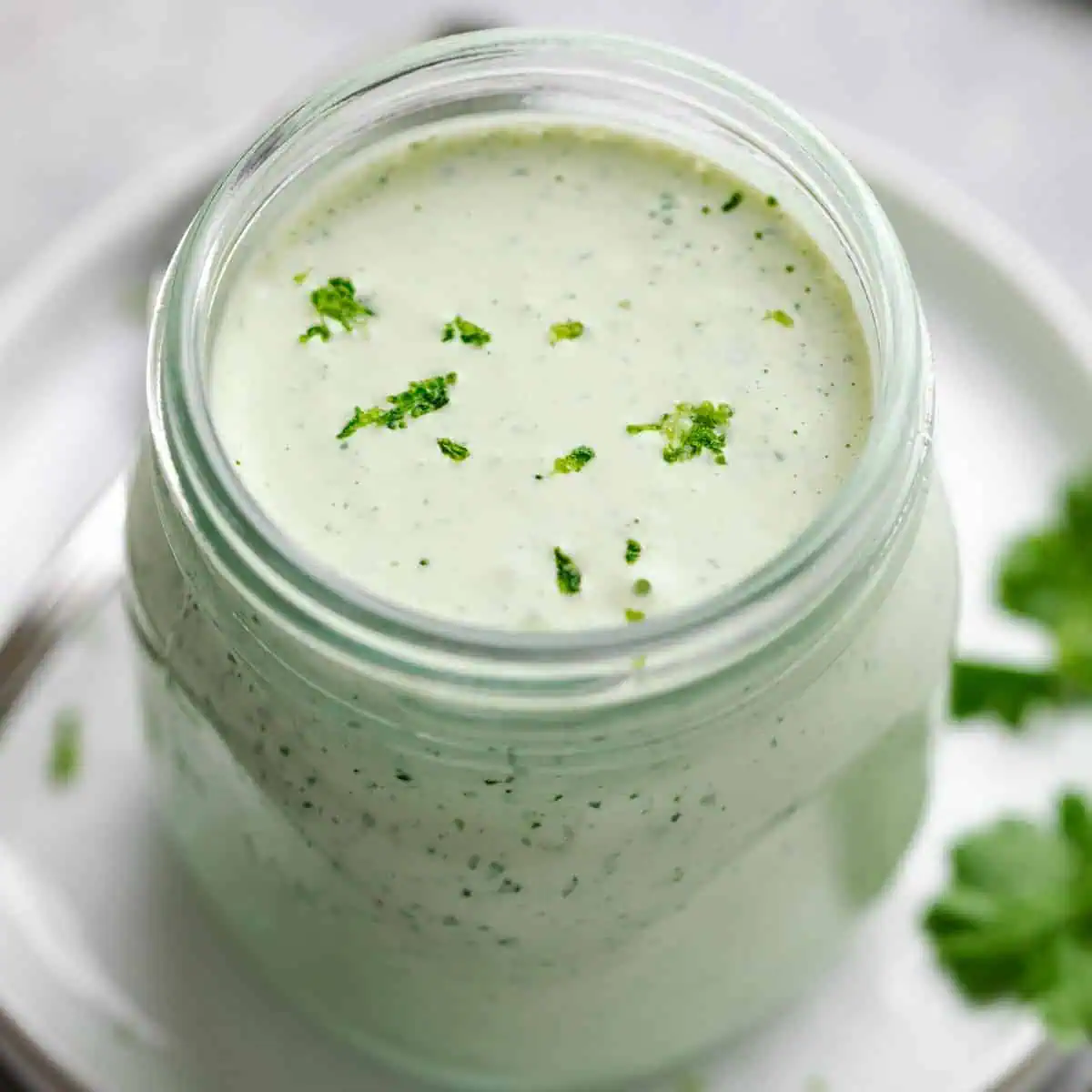 Jar of cilantro lime crema on a plate.