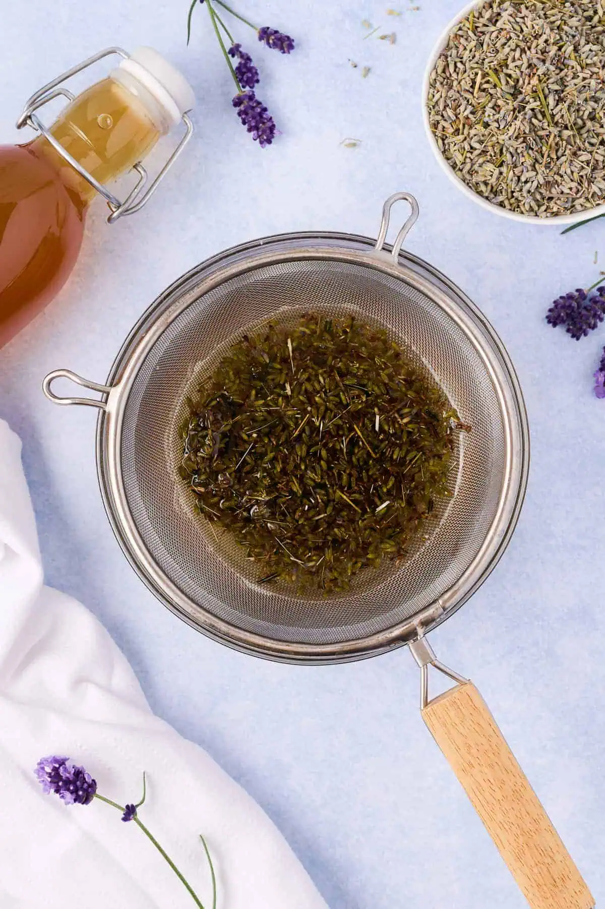 Lavender simple syrup poured through a mesh strainer.