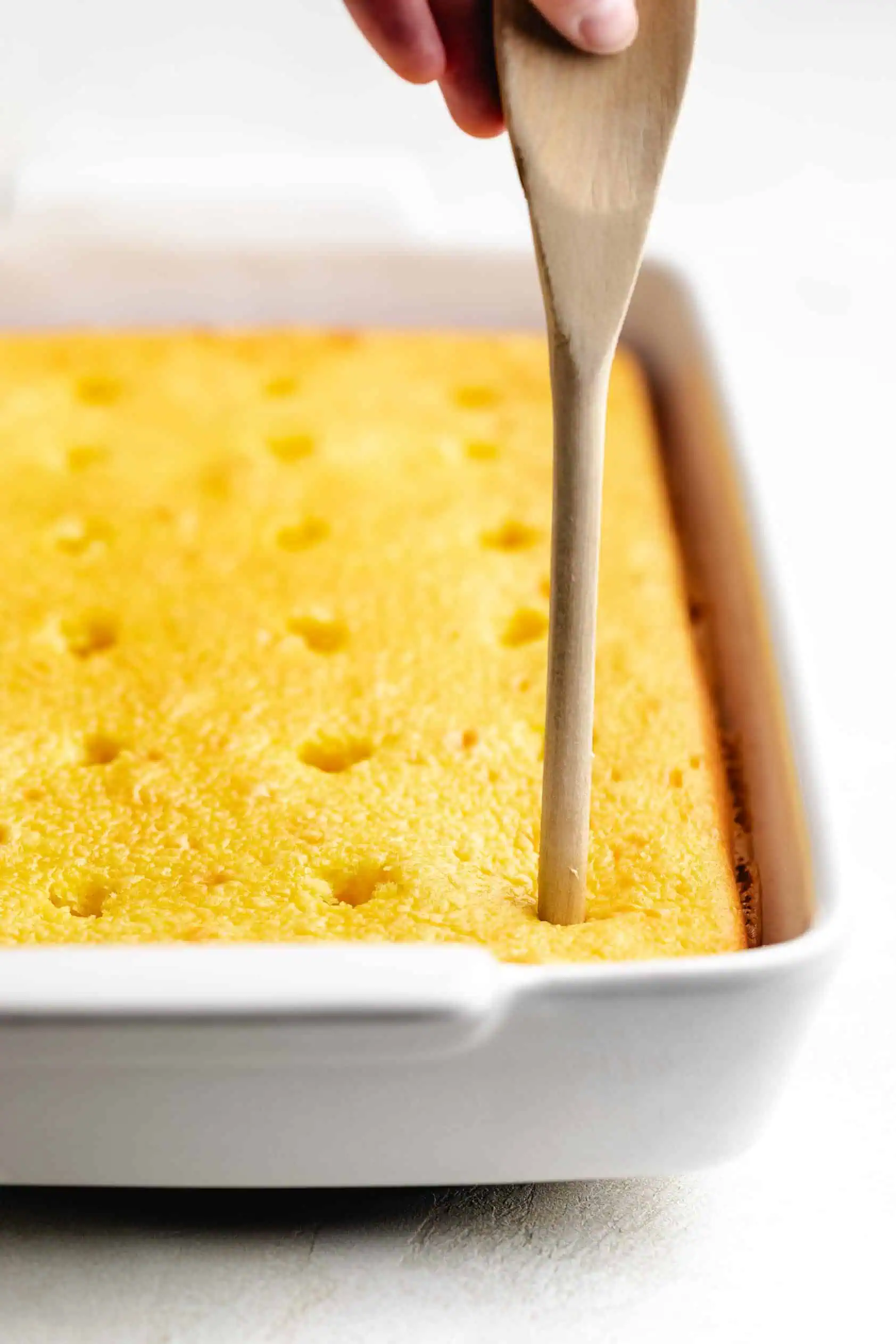 Spoon poking holes into a cake.