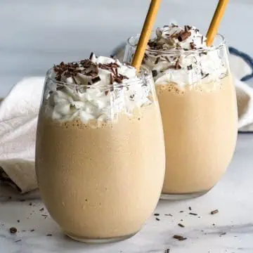 Two boozy milkshakes in glasses with whipped cream.