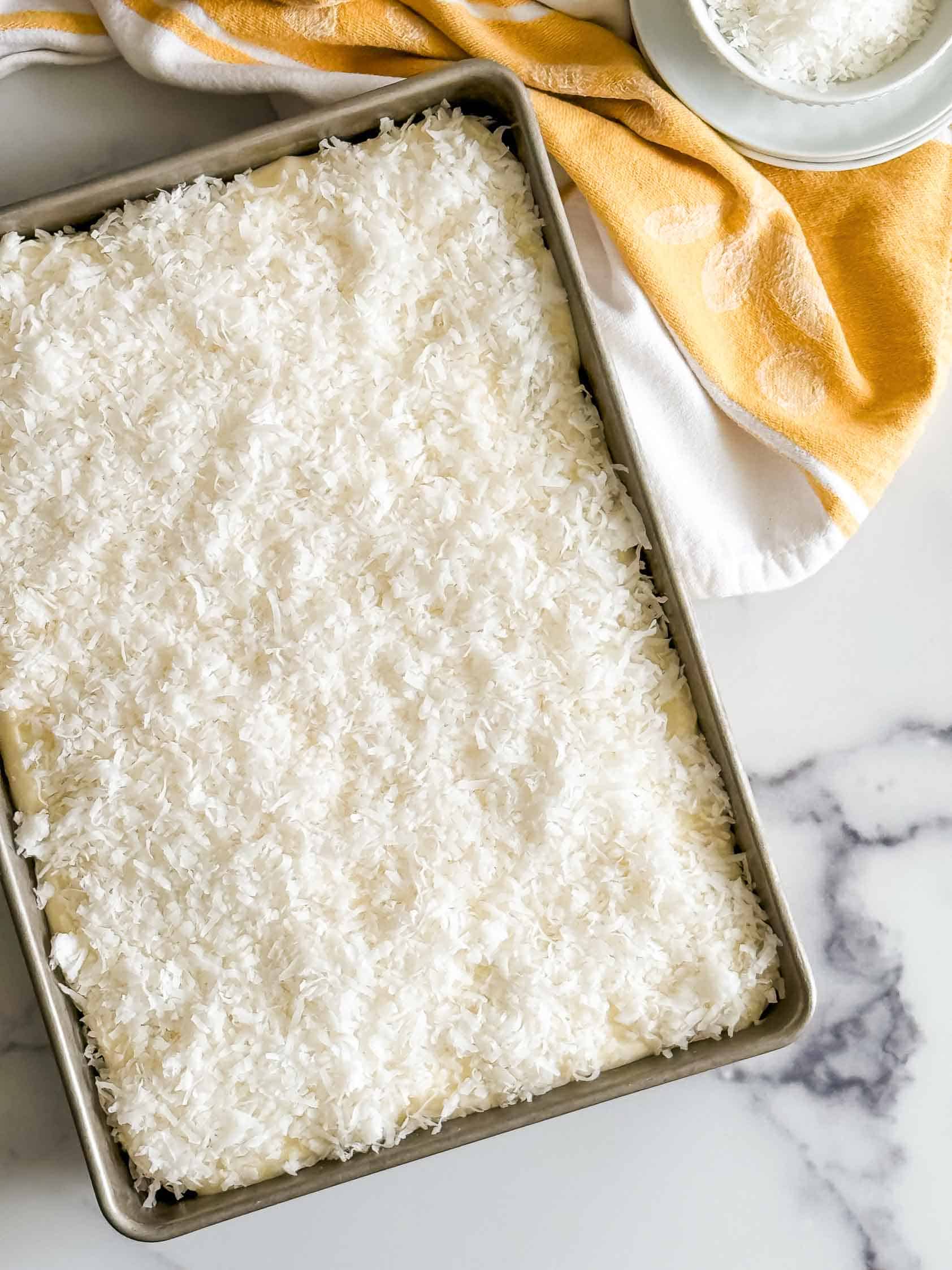White cake in a pan with coconut cream cheese frosting.