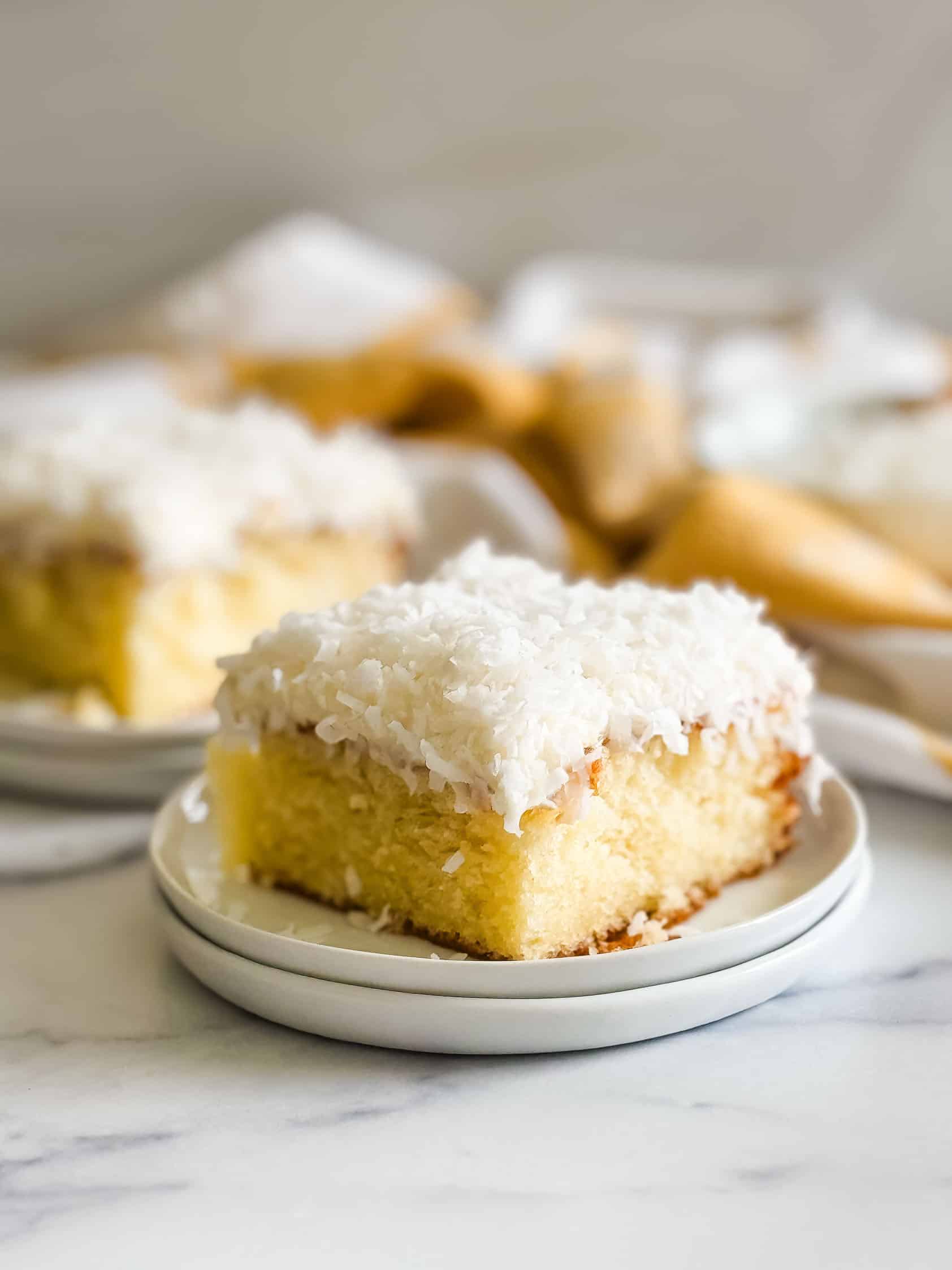 Slice of coconut cake on a white plate.