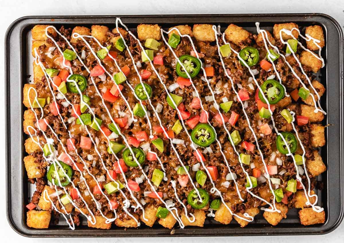 Pan of tater tot nachos with ground beef and toppings.