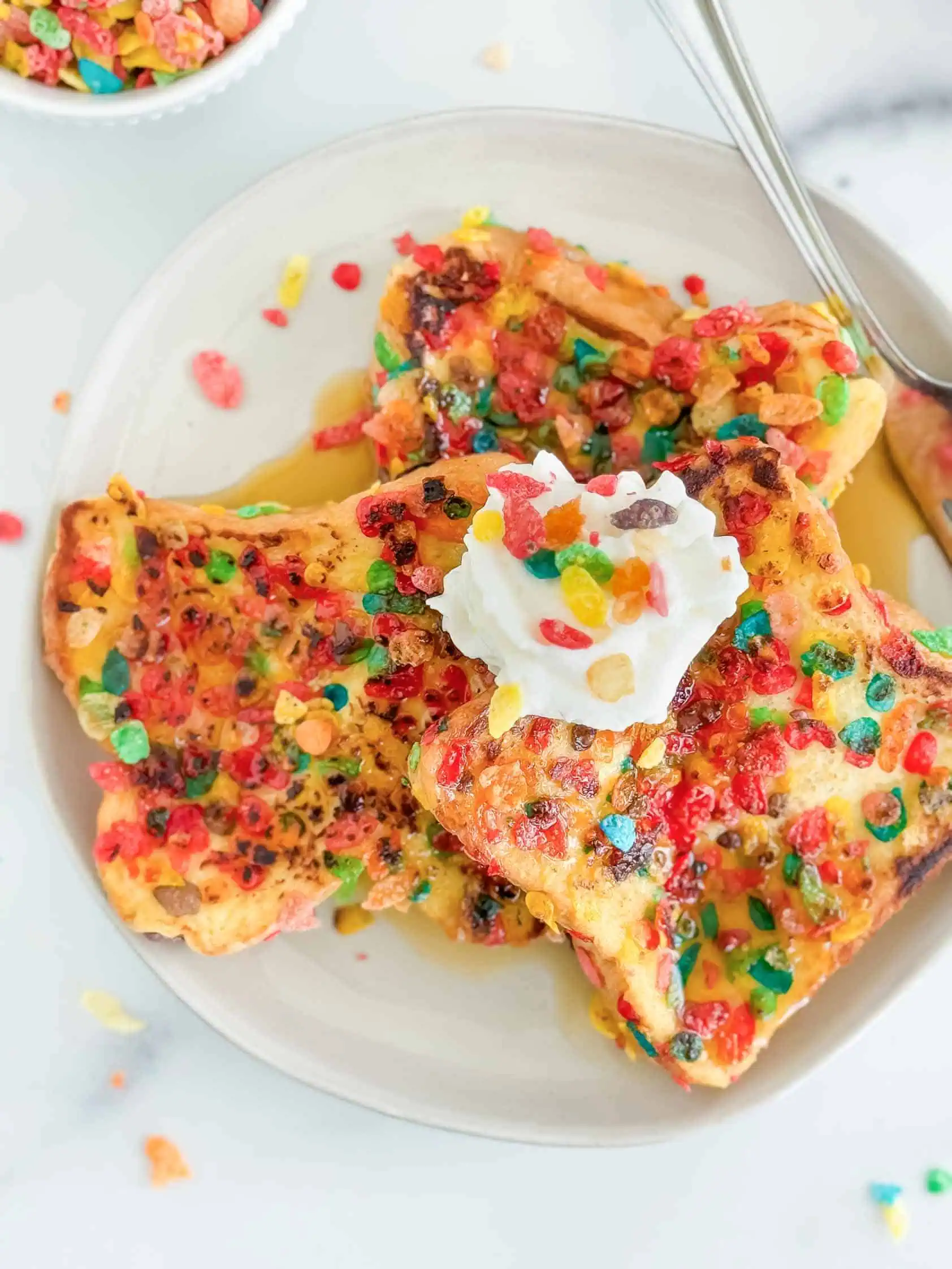 Three slices of fruity pebbles french toast on a plate.