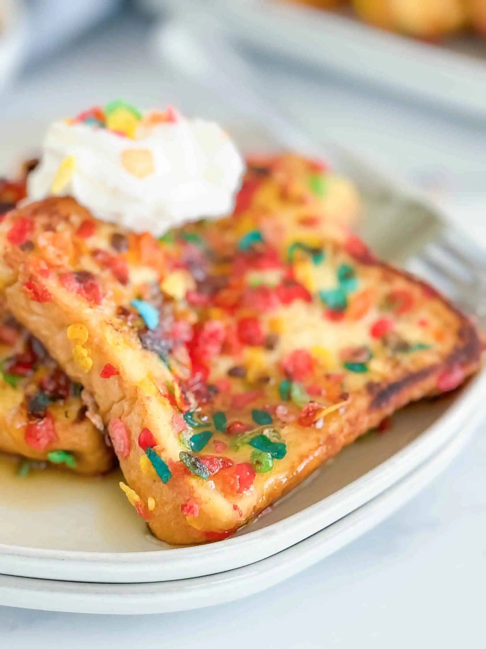 Whipped cream on top of cereal crusted french toast.