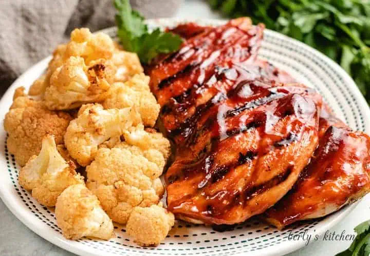 Grilled chicken with bbq sauce next to cauliflower.