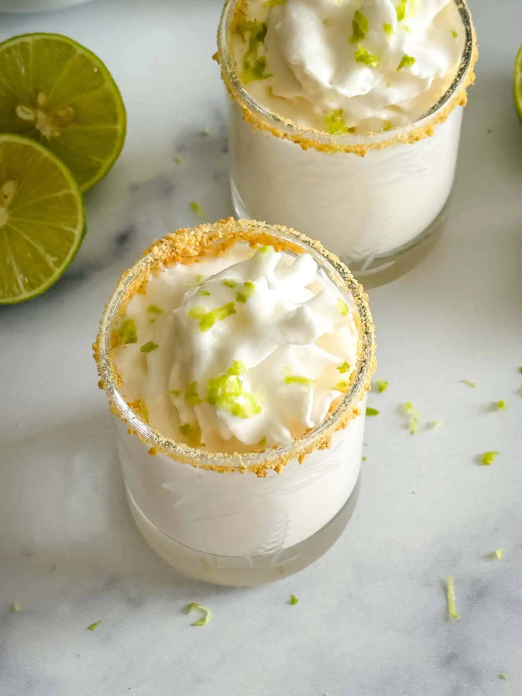 Lime zest and whipped cream on top of key lime pie shot.