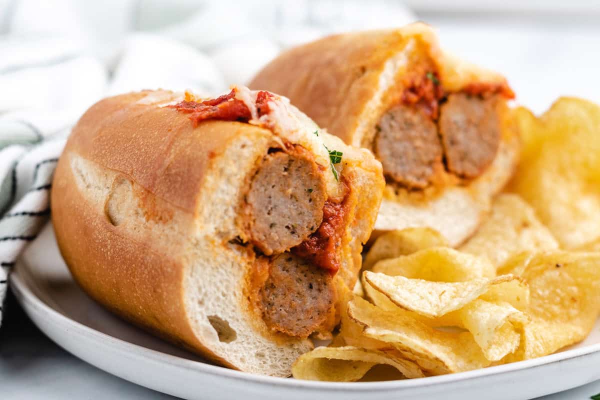 Meatball sub cut in half next to potato chips.