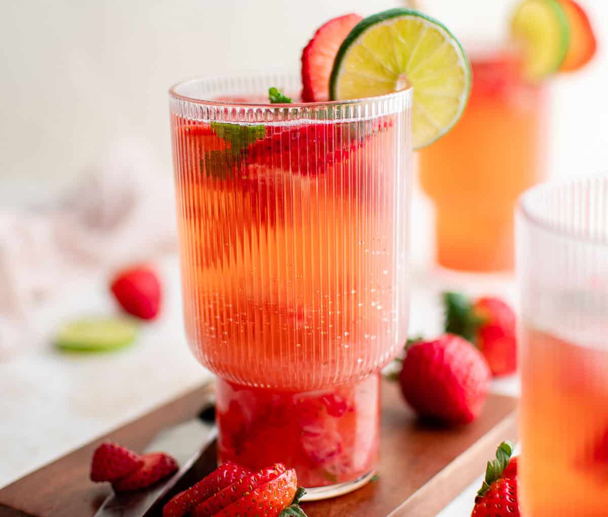 Side view of a strawberry mojito on a wooden board.