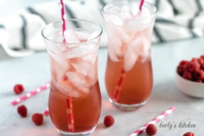 Two glasses of raspberry italian soda with pink straws.